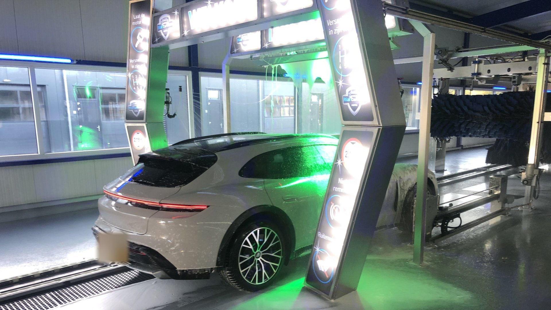 Een auto rijdt bij groen licht onder de WELKOM-boog de wasstraat in